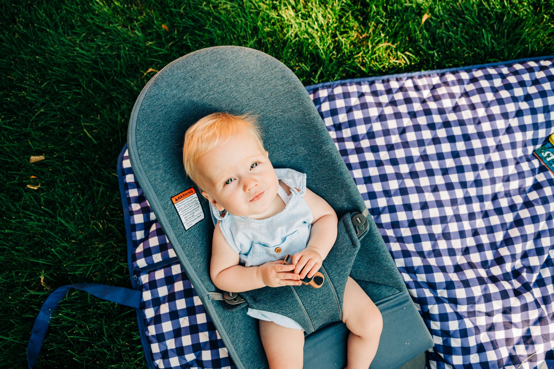 baby sitting in a carrier on a blanket