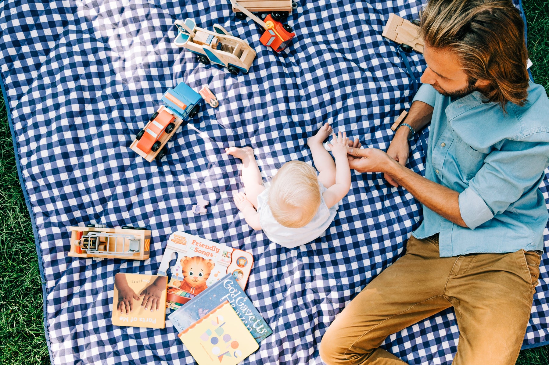 a toddler sitting outside on a blanket with dad 