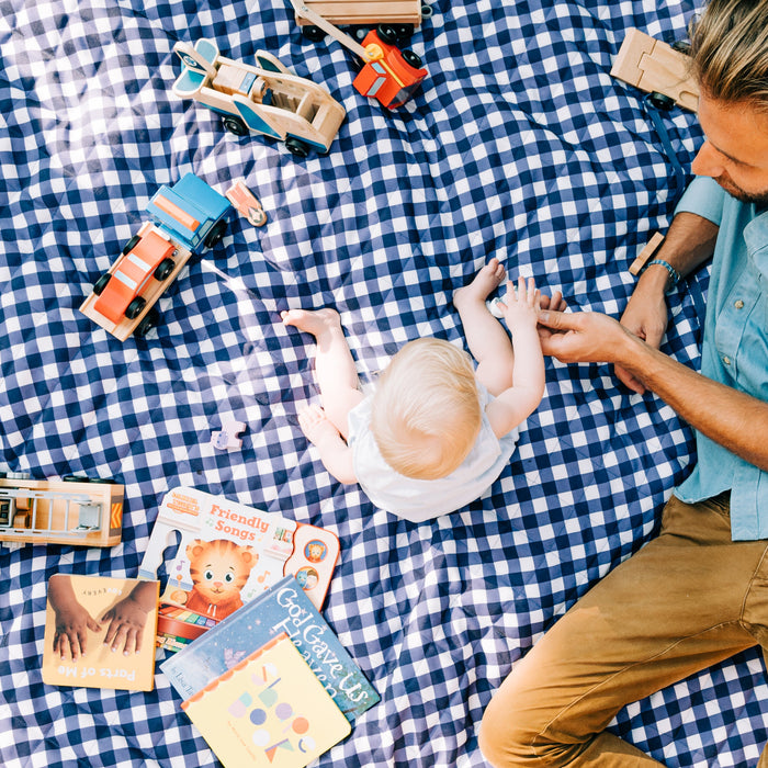 a toddler sitting outside on a blanket with dad 