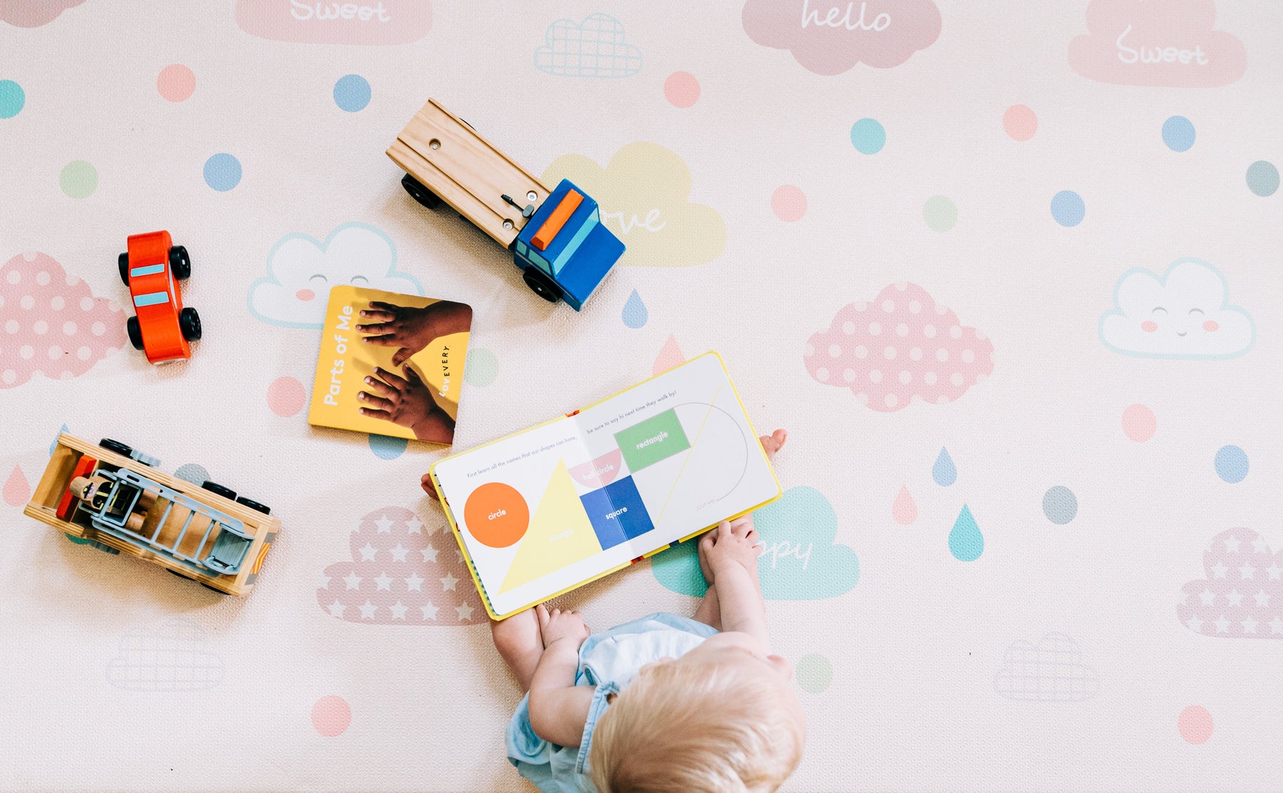 a toddler playing with interactive toys on a colorful play mat 