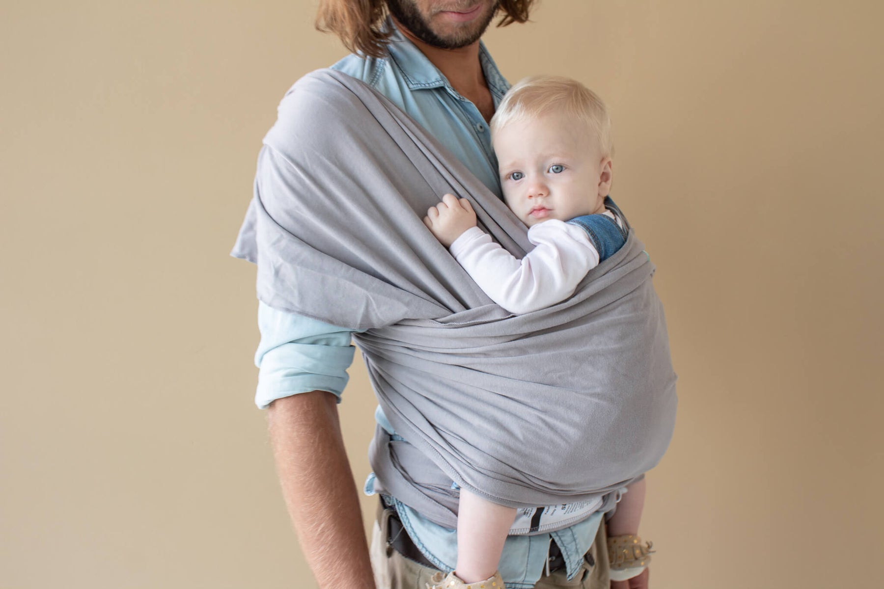 father using a grey baby wrap with his baby in it 