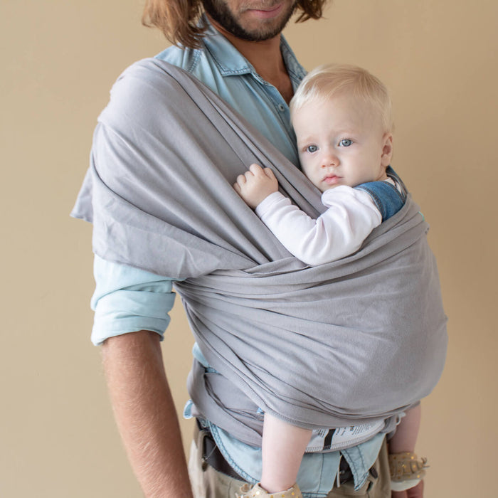 father using a grey baby wrap with his baby in it 