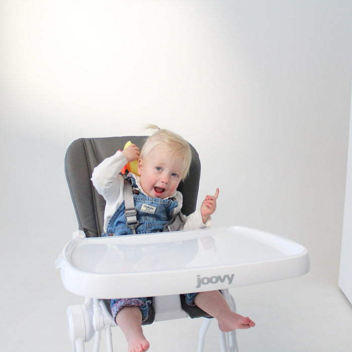 blonde haired little girl sitting in the Joovy high chair smiling