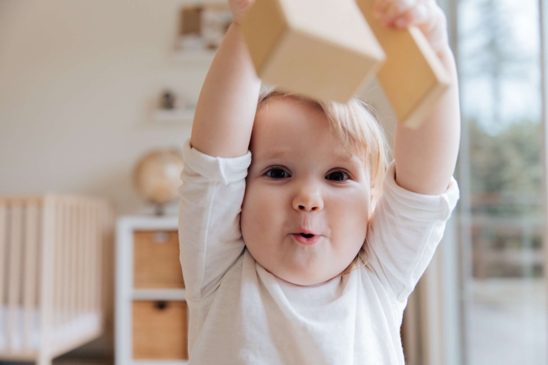 baby holding up non toxic wooden toy