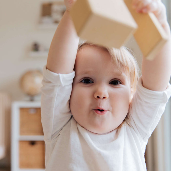 baby holding up non toxic wooden toy