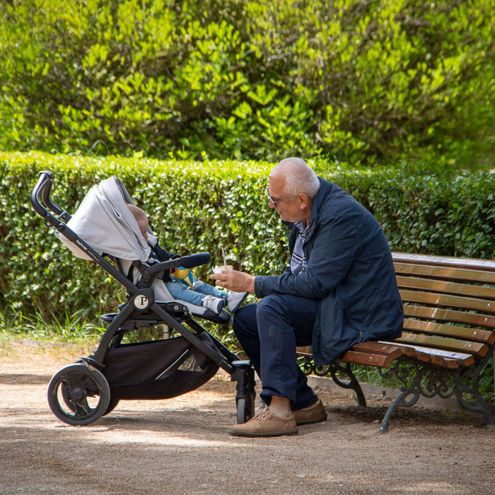 grandpa with his grandkid at a park with a stroller