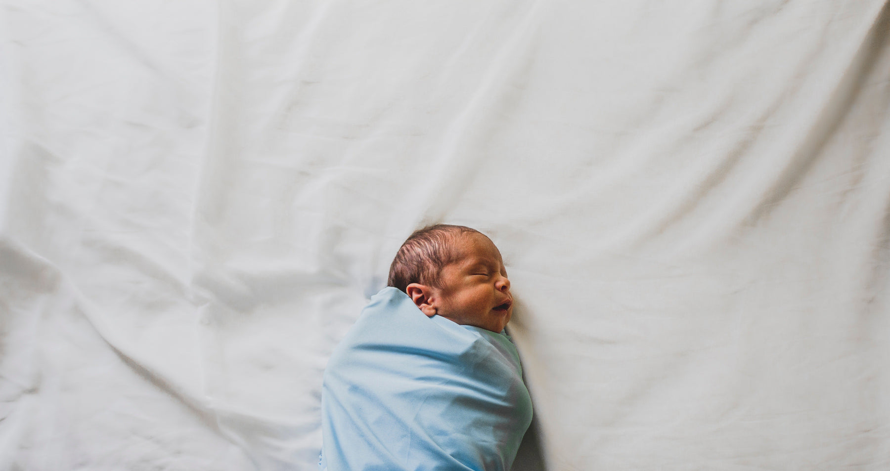 a baby sleeping safely in a swaddle 