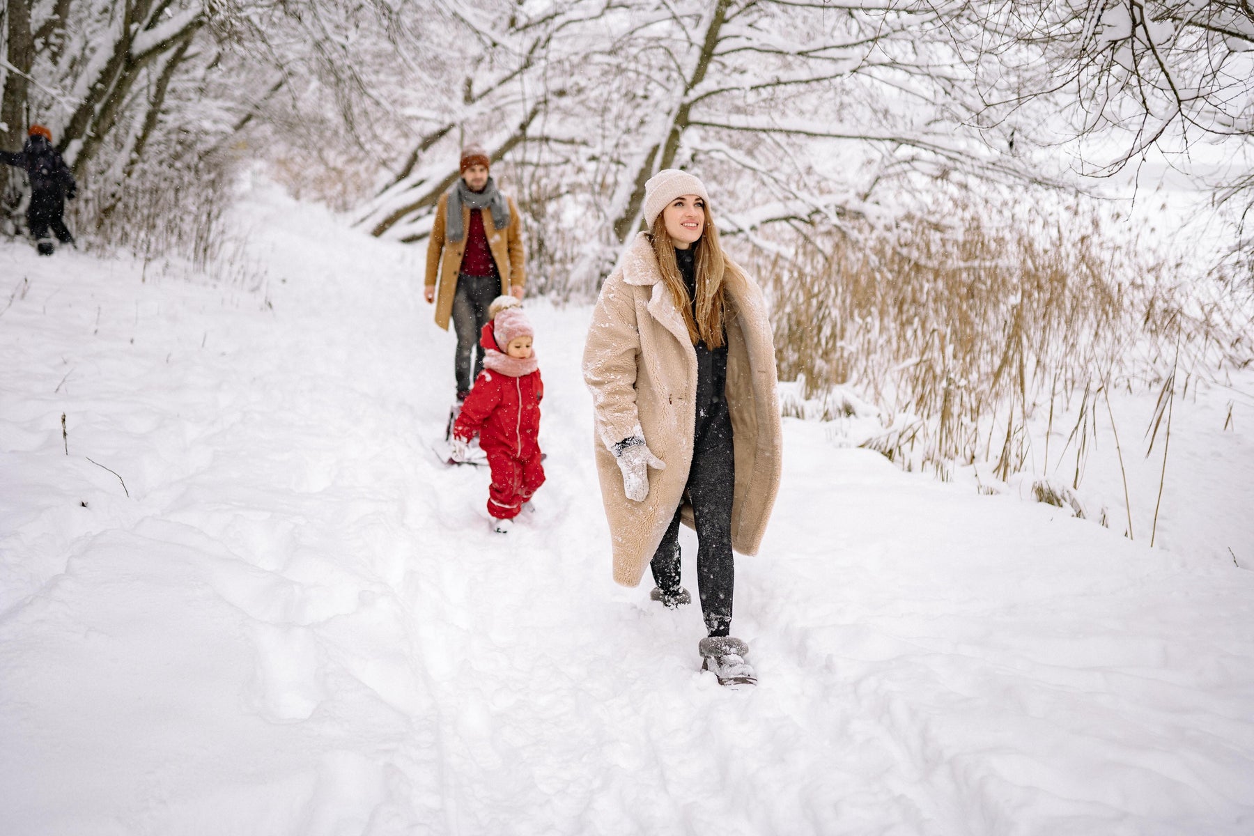 family with a toddler walking in the snow during winter 