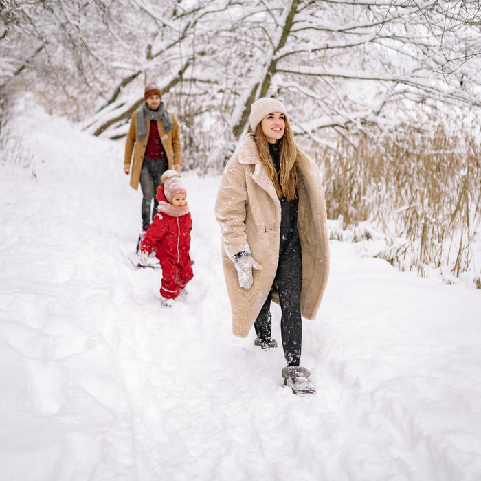 family with a toddler walking in the snow during winter 