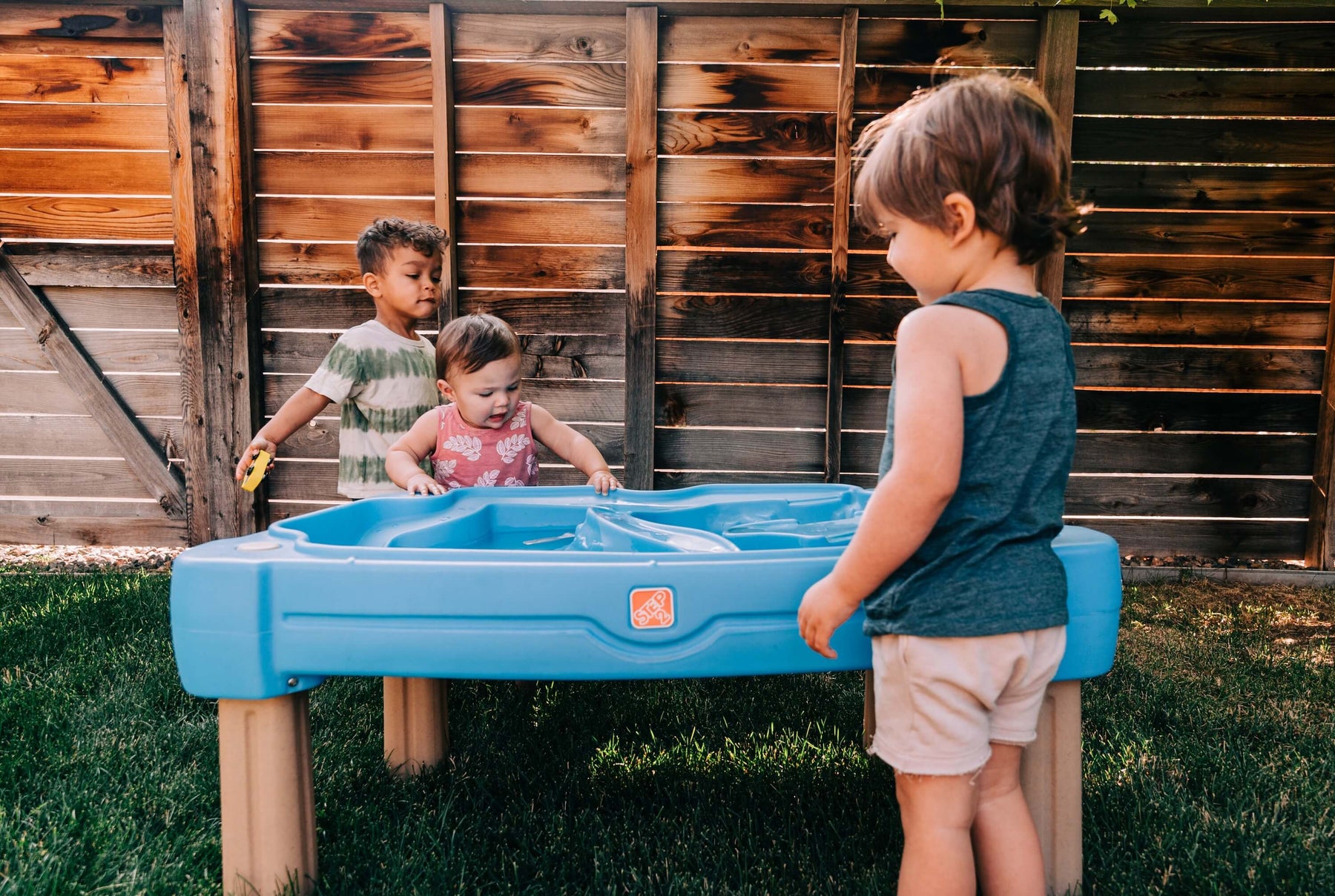 kids playing outside in the summer with a water table