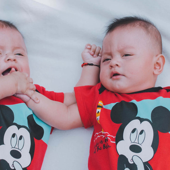 twins sleeping next to each other in matching Mickey Mouse pajamas 