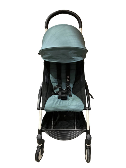 Teal stroller in a warehouse setting with cardboard boxes in the background