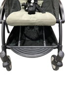 Black stroller with beige cushion on a light gray floor