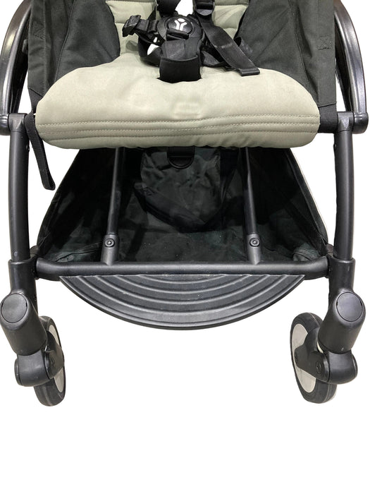 Black stroller with beige cushion on a light gray floor