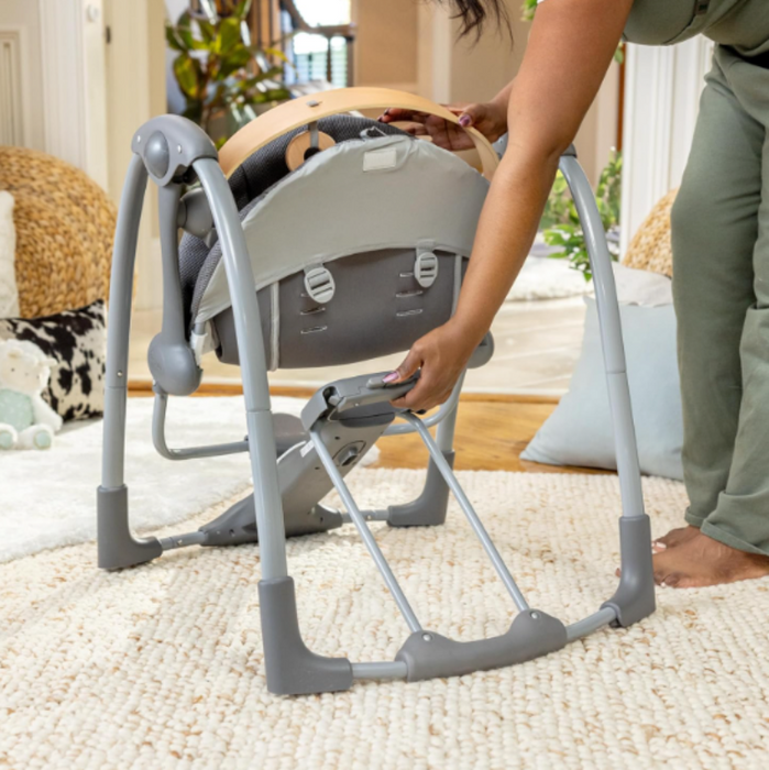 Baby swing being adjusted by a person in a home setting