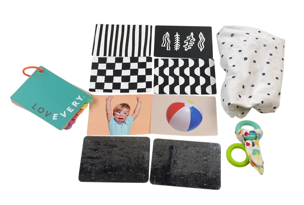 Collection of baby items including a blanket, cards, and toys on a white background